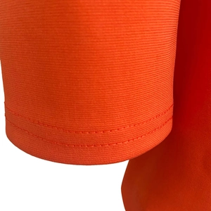 Detailed macro view of orange knit fabric texture with double-needle stitching seams
