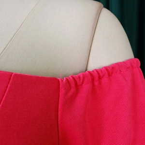 Close-up of the pleated elastic neckline and textured fabric on a rose pink dress