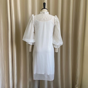 Detail view of white mesh dress with puff sleeves and ruffled collar back button