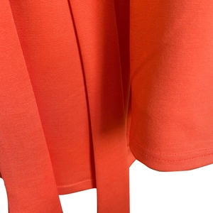 Detailed macro view of coral orange dress fabric showing rib texture and stitching