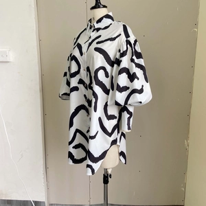 Detailed macro view of the abstract black brushstroke pattern on a white shirt dress
