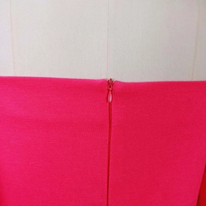 Detail view of the rose red knitted fabric texture and seamless invisible zipper closure