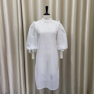Detail view of white lattice hollow dress featuring high neck ruffle and puff sleeves