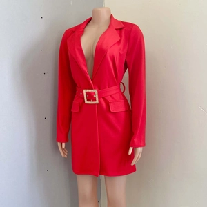 Dettaglio dell'abito blazer rosso con scollo a V profondo e cintura con fibbia dorata