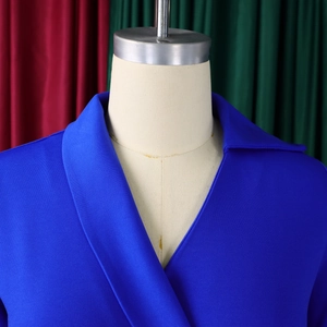 Détail de la robe bleu roi à col en V et du revers sur un mannequin beige élégant