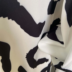 Detailed view of soft satin fabric with abstract black and white patterns and silky gloss
