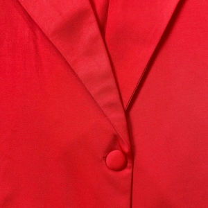 Dettaglio ravvicinato di un abito a blazer rosso con revers e bottone rivestito in tessuto