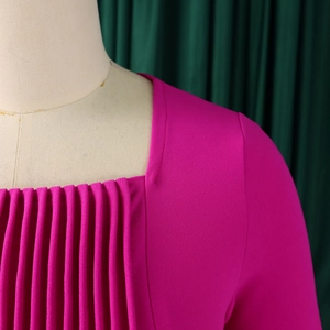 Detail view of rose pink square neck dress featuring vertical pleated bodice and woven texture