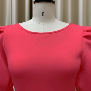 Détail de la robe rose corail à manches bouffantes avec col rond élégant sur mannequin