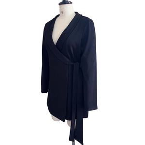 Detail view of black long sleeve wrap blazer dress with waist tie on a mannequin