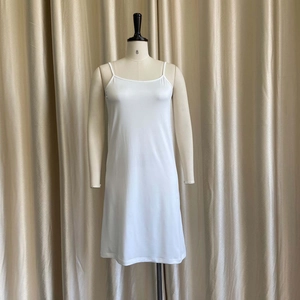 Detail of white silk slip dress with thin straps and smooth finish on a mannequin