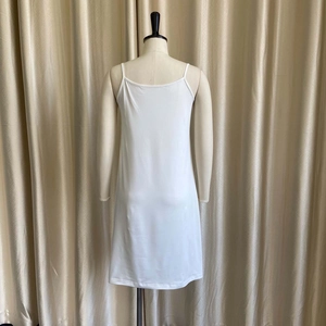 Detail showing white spaghetti strap slip dress with satin finish and minimalist cut