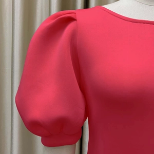 Détail de la manche bouffante rose fuchsia avec plis élégants et tissu de haute qualité