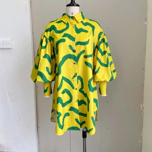Detail view of the yellow puff sleeve and deep green abstract print on this shirt dress