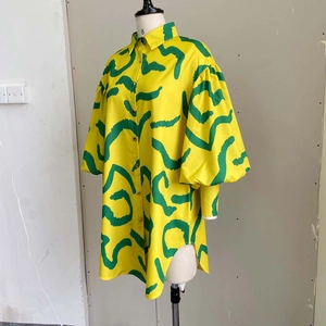 Detail of yellow shirt dress with green wave pattern, puff sleeves and side slit hem