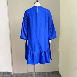 Detail view of royal blue puff sleeve dress with keyhole back button and pleated hemline