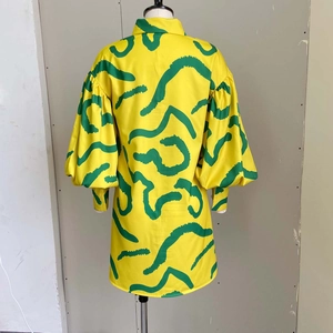 Detailed view of yellow long-sleeve shirt dress with green abstract pattern and lantern sleeves