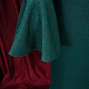 Detailed view of dark green flare sleeves with textured twill fabric and heavy drape
