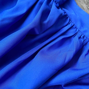 Close-up of royal blue pleated fabric texture and stitching on the puff sleeve dress