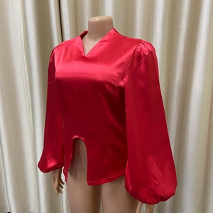 Dettaglio della camicetta di raso rosso con scollo a V e eleganti maniche a lanterna