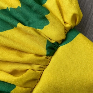 Close-up of fabric showing vibrant yellow and dark green floral patterns with textile texture