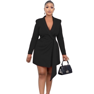 Detail of a slim-fit black blazer dress featuring a red contrast lining and a waist tie