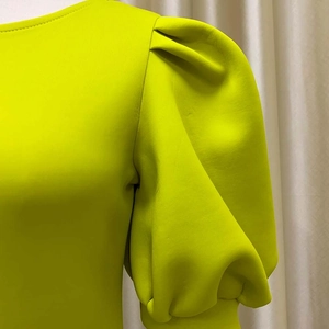 Détail des manches bouffantes jaune néon et texture plissée d'une robe de soirée chic