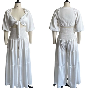 Dettaglio del completo bianco due pezzi con top con scollo a V e pantaloni larghi a balze