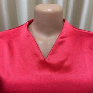 Dettaglio ravvicinato dell'elegante camicia in raso rosso con scollo a V e trama setosa