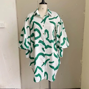 Detail of the abstract green print on a white button-down shirt dress with lantern sleeves