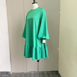 Detail of green long sleeve dress with puff sleeves and ruffled hem on mannequin