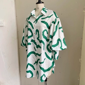 Detailed view of white and green abstract print satin shirt with golden buttons