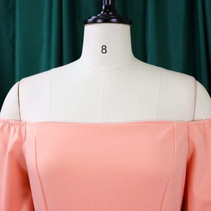 Detail of peach pink off-the-shoulder dress showing smooth fabric texture and shoulder line