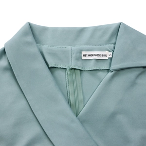 Détail du col en V avec fermeture éclair invisible et étiquette sur une robe vert sauge