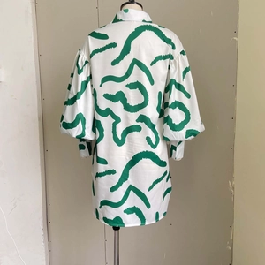 Detail view of white shirt dress featuring green abstract print and puff sleeve design