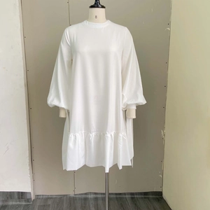 White long puff sleeve dress with crew neck and pleated ruffle hem on a mannequin