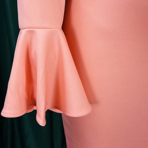 Detail of coral pink bell sleeves with high-quality knit texture and smooth draping fabric
