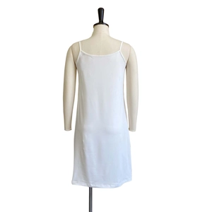 Detail view of a white slip dress featuring thin spaghetti straps and a smooth sleek fabric