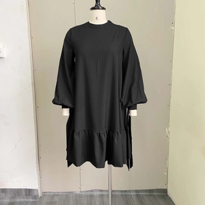 Detail of loose black dress featuring lantern sleeves and ruffled hem on a mannequin