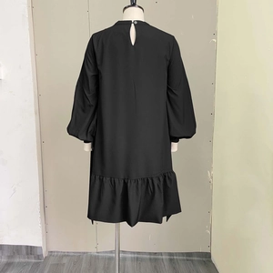Detail view of black dress featuring puff sleeves and rear keyhole closure on a mannequin