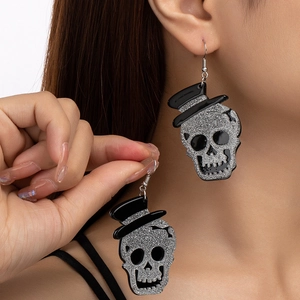 Close-up of glitter skull earrings with black top hats worn on ear for party look
