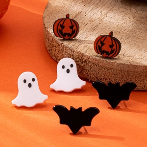 Detailed view of Halloween earring set with pumpkin, ghost, and bat studs on a wood stand