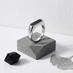 Macro shot of silver stainless steel ring with black rectangular inlay on stone pedestal