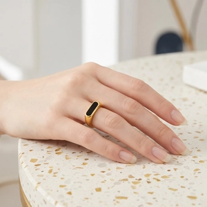 Gold stainless steel signet ring with black rectangular shell inlay on female hand