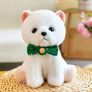 Close-up of white fluffy puppy plush toy with a green bow tie on a woven mat