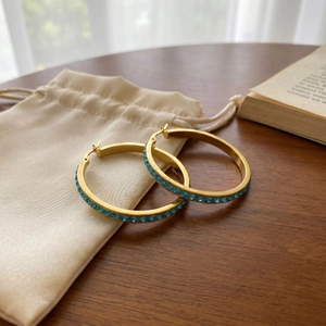 Macro shot of 40mm gold hoop earrings with sea blue rhinestones and drawstring pouch
