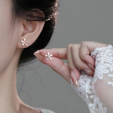 Detailed view of silver flower stud earrings with pearl white petals and small crystals
