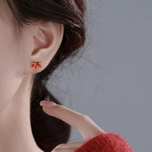 Close-up of red maple leaf earrings with gold trim worn on ear for a minimalist look