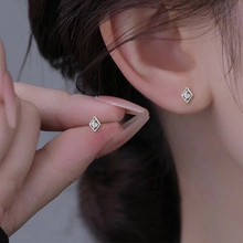 Macro view of minimalist silver star-shaped stud earrings featuring small sparkling zircons