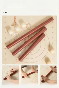 Three sizes of solid ebony wood rolling pins on a baking mat with flour and dough